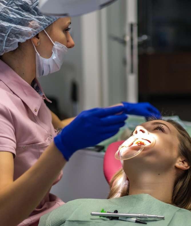 A patient lying in a dental chair with mouth open while a dental professional examines their teeth.