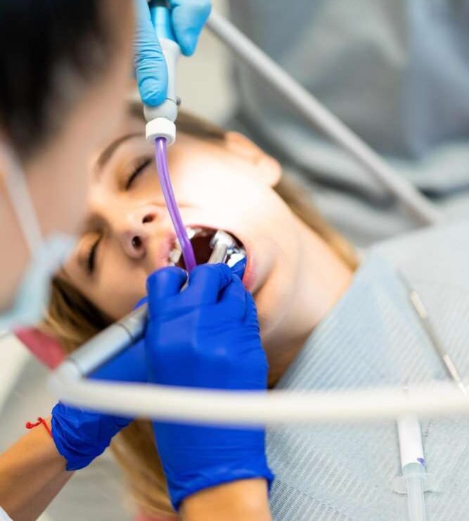 Close-up of a patient receiving dental treatment with dental instruments.