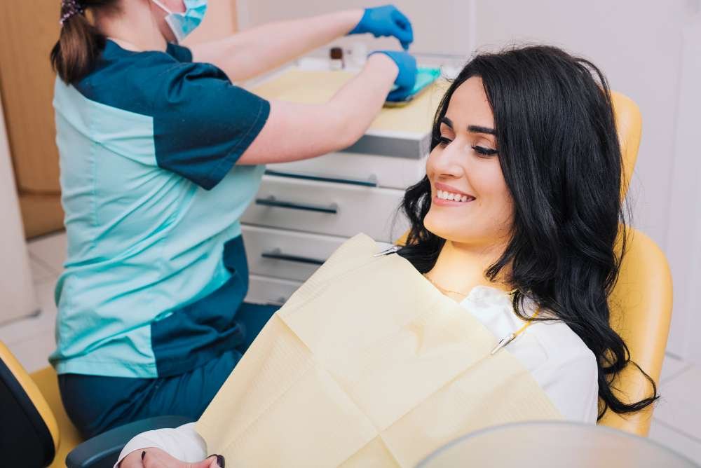 A smiling woman sitting in a dental chair during a cosmetic dentistry appointment.