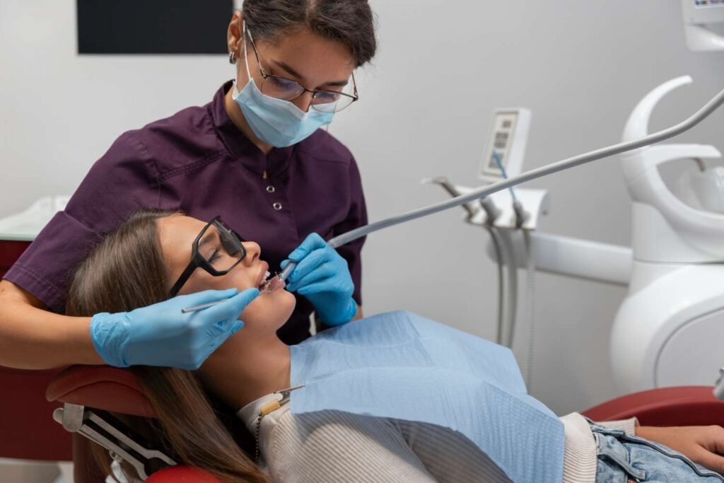 A dentist performing a cosmetic dental procedure on a patient wearing protective glasses.
