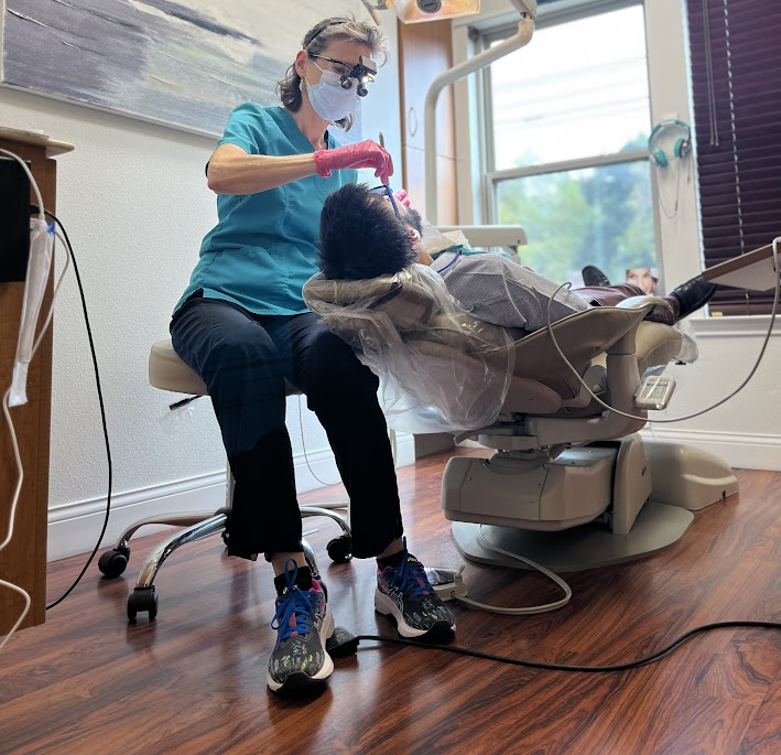 A dentist treating a patient in a dental chair during an emergency visit.