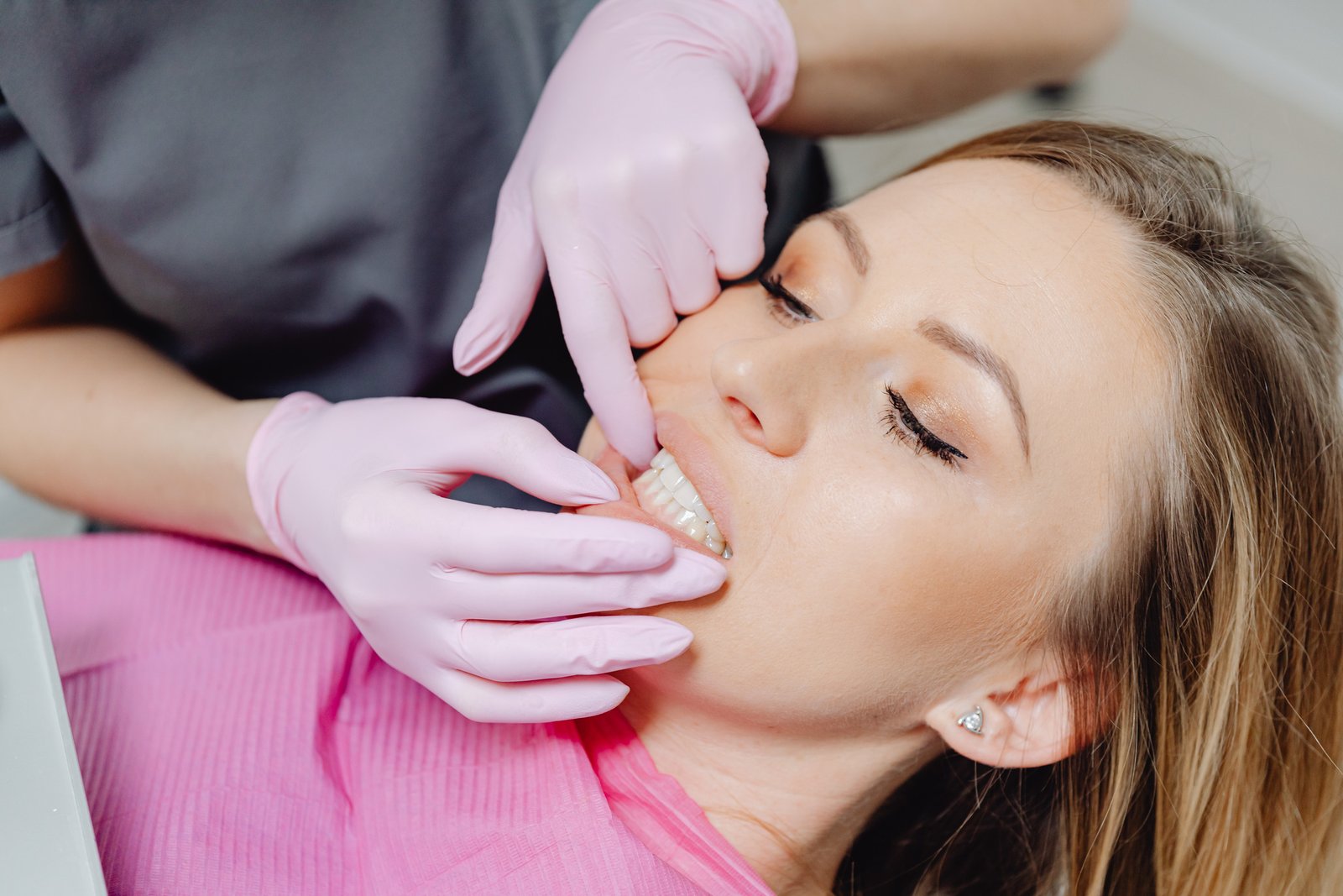 A dentist examining a woman’s gums during a dental checkup.