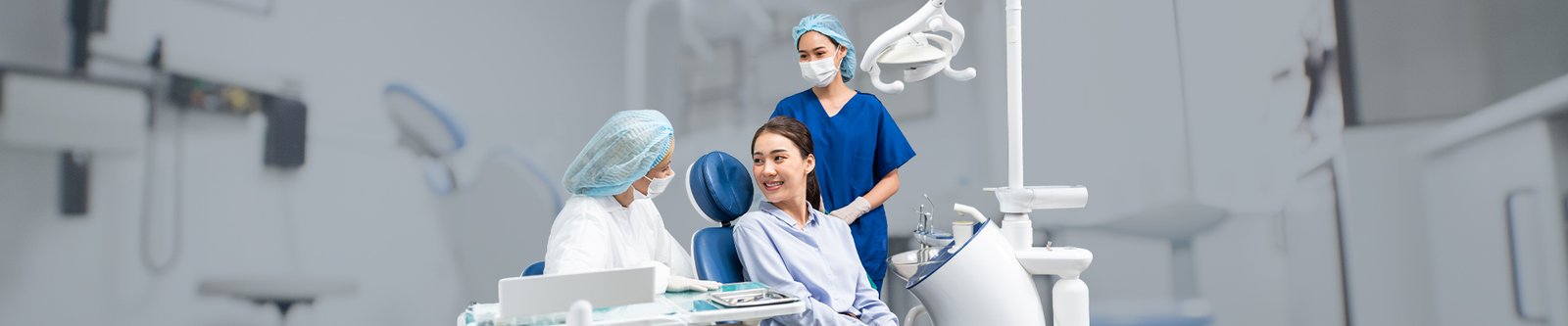 Patient sitting in a dental chair smiling while talking with dental staff.